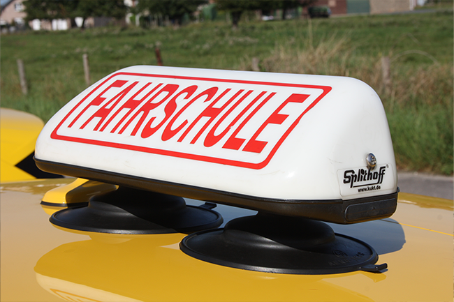 Ein Schild auf einem gelben Auto sagt Fahrschule