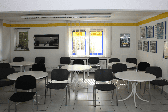 Ein Raum mit Tischen und Stühlen und einem Fenster