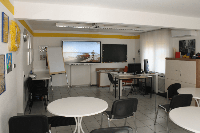 Ein Raum mit Tischen und Stühlen und einem großen Flachbildfernseher