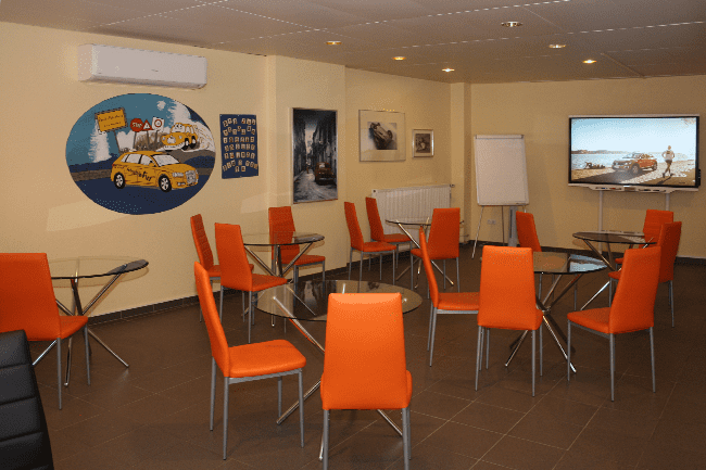 Ein Raum mit Tischen und Stühlen und einem Gemälde eines Taxis an der Wand