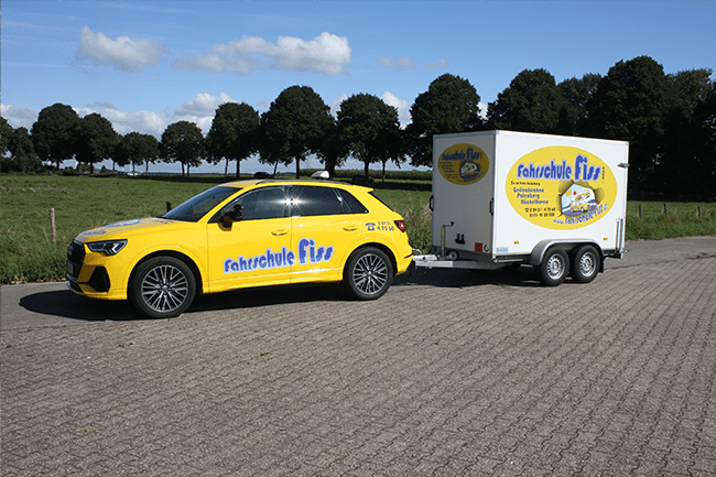 Ein gelbes Auto zieht einen weißen Anhänger mit der Aufschrift „Nieuwe fur“