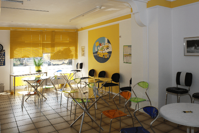 Ein Raum mit Tischen und Stühlen und einem Gemälde eines gelben Busses an der Wand