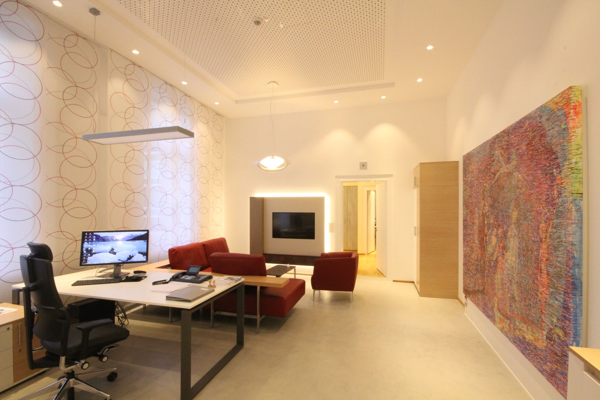 Ein Wohnzimmer mit einer Couch und einem Schreibtisch mit einem Computer darauf