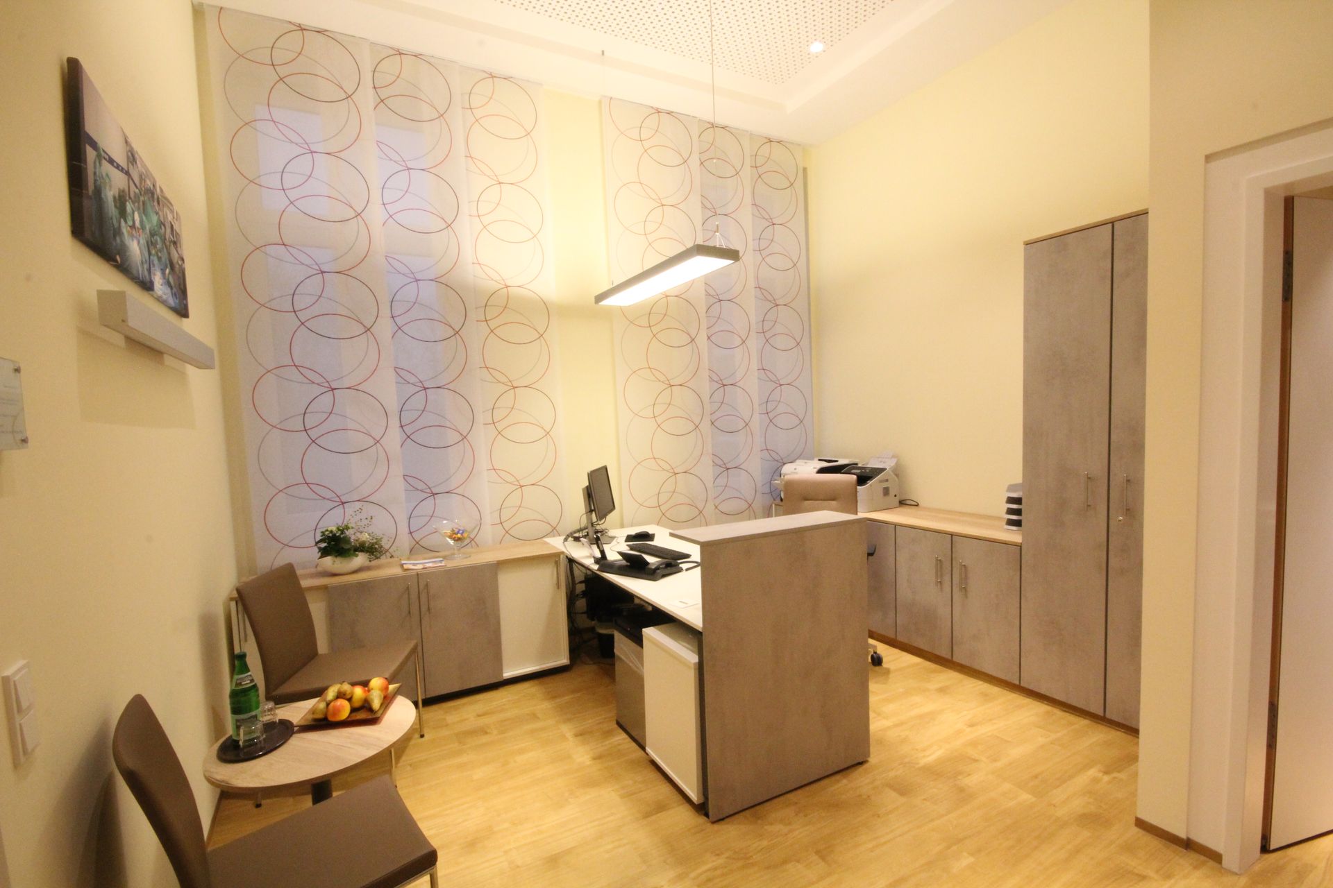 Ein Zimmer mit einem Schreibtisch und Stühlen darin