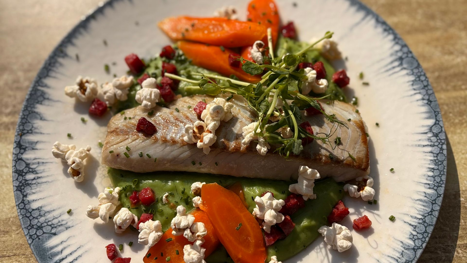 Poisson grillé accompagné de purée de petits pois, de carottes, le tout servit dans une assiette à bord bleu.