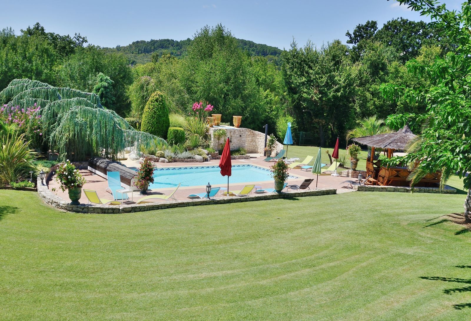 Piscine entourée de verdure et d'une petite gloriette.