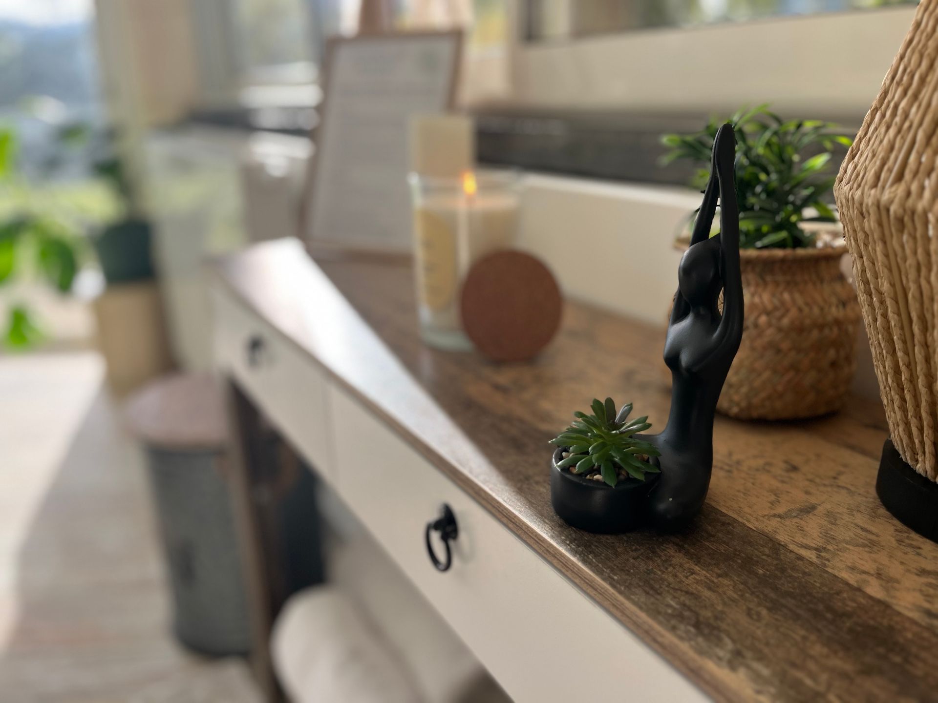 Étagère en bois avec objets décoratifs : figurine de yoga, plante grasse, bougie et panier tressé
