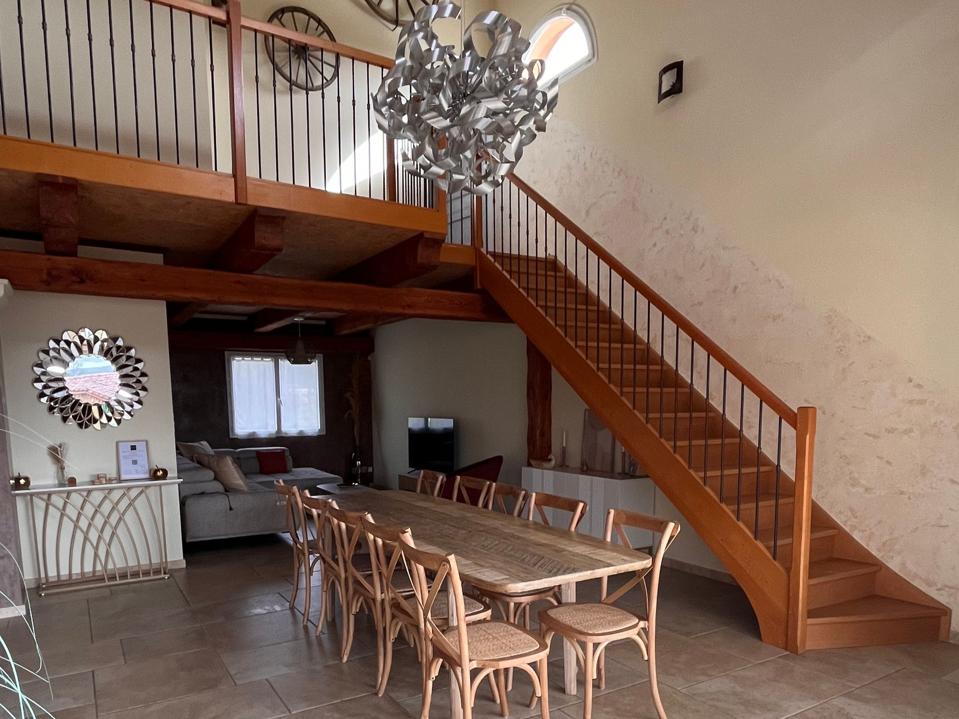 Salle à manger avec grande table, chaises et escalier menant aux chambres