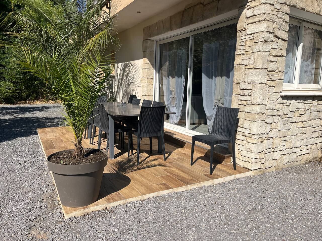 Terrasse extérieure avec table à manger et palmier en grand pot