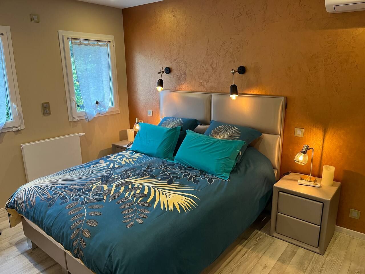 Chambre avec lit double, linge de lit bleu et or à motif végétal