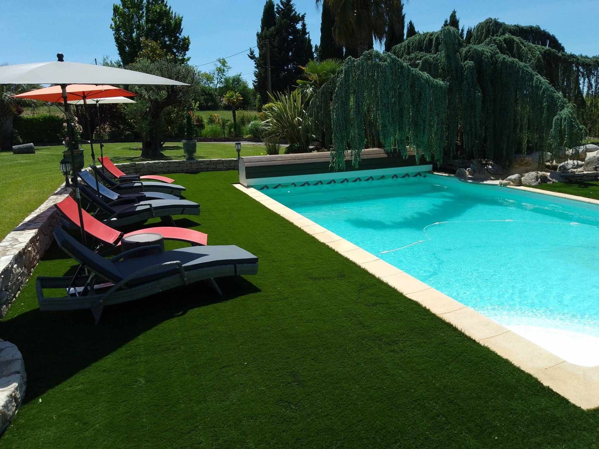 Piscine entourée de verdure et d'une petite gloriette. 
