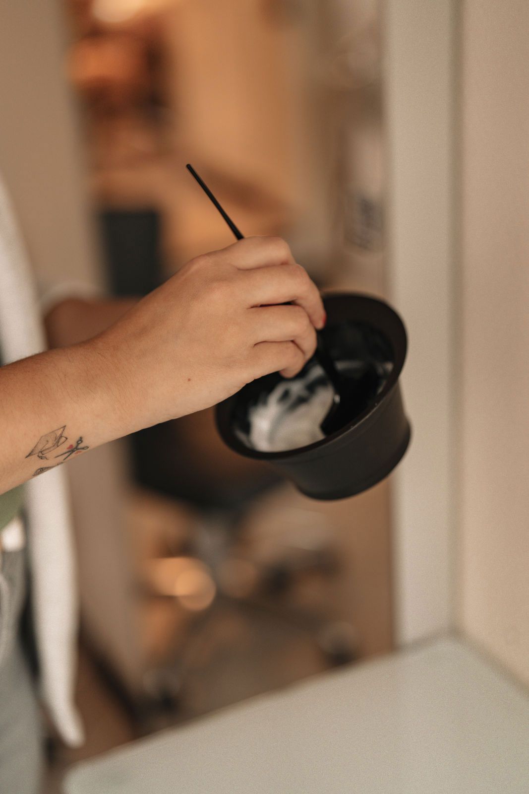 Eine Person mischt mit einem Pinsel Haarfärbemittel in einer Schüssel.