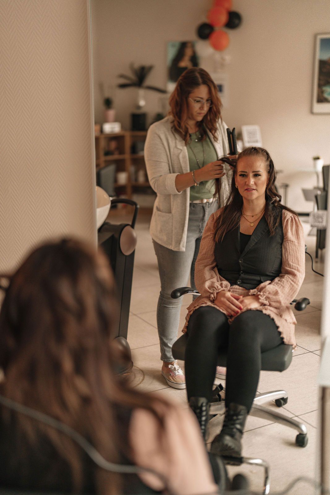 Eine Frau sitzt auf einem Stuhl und lässt sich von einem Friseur die Haare machen.