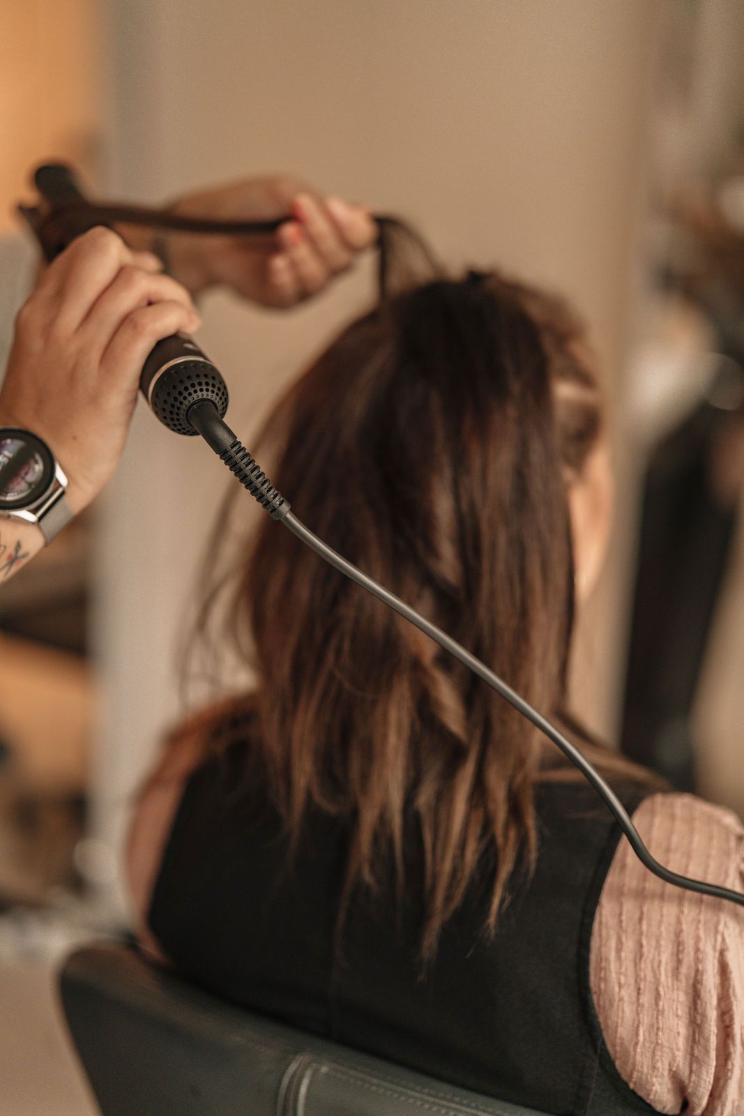 Eine Frau lässt sich von einem Friseur die Haare glätten.