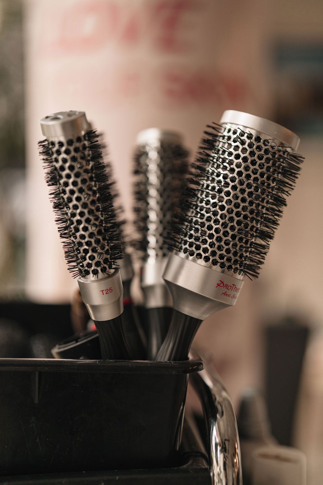 Ein Haufen Haarbürsten liegt in einem Eimer auf einem Tisch.