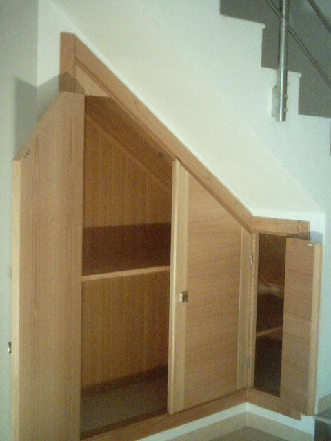 Un armario debajo de una escalera con las puertas abiertas.