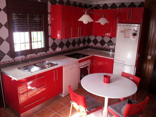 Una cocina con gabinetes rojos y una mesa blanca.