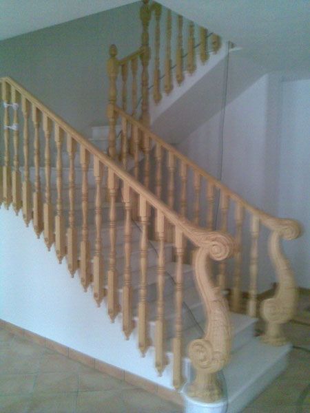 Una escalera de madera con una estatua en la barandilla.