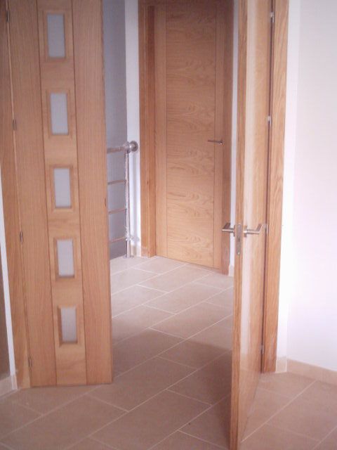 Un pasillo con dos puertas de madera y suelo de baldosas.