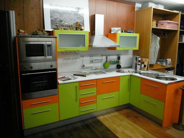 Una cocina con gabinetes verdes y naranjas y un microondas.