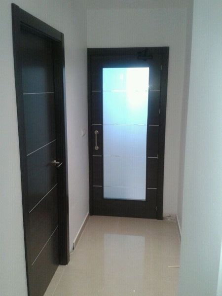 Un pasillo con dos puertas y una puerta de cristal.