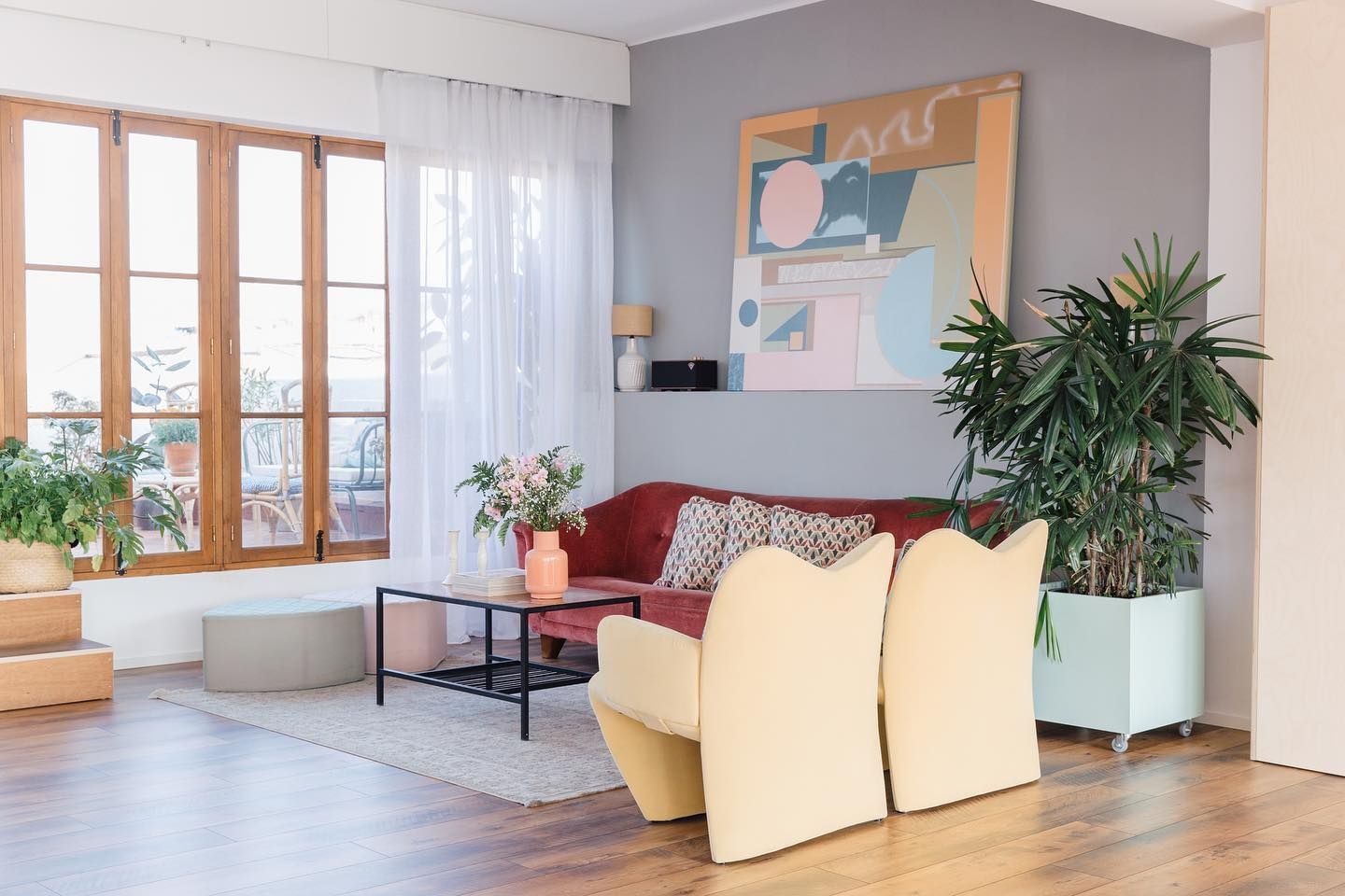 Sala de estar con sofá rojo, sillas amarillas y obras de arte en una pared gris.