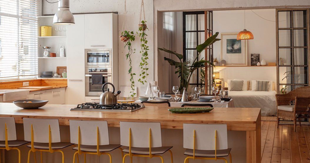 Acogedora cocina con isla de madera, sillas amarillas y puerta abierta al dormitorio.