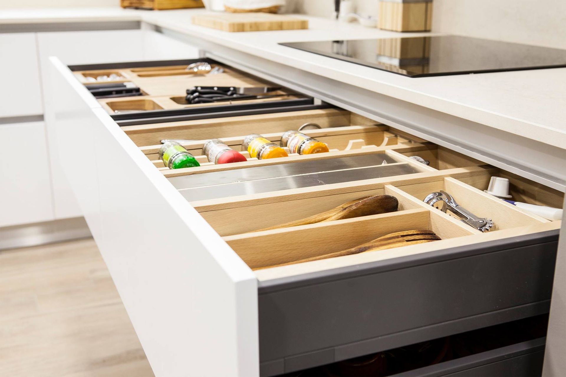 Cajón de cocina abierto con utensilios, cuchillos y especias organizados.