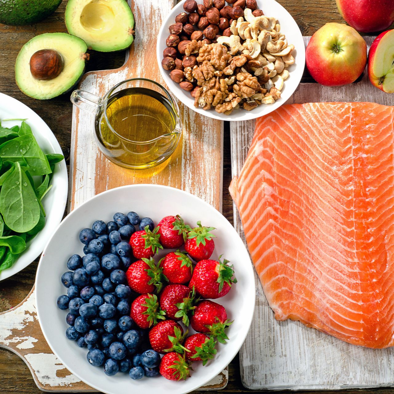 Assortiment d'aliments sains : saumon, baies, avocat, noix, épinards et huile d'olive sur une table rustique