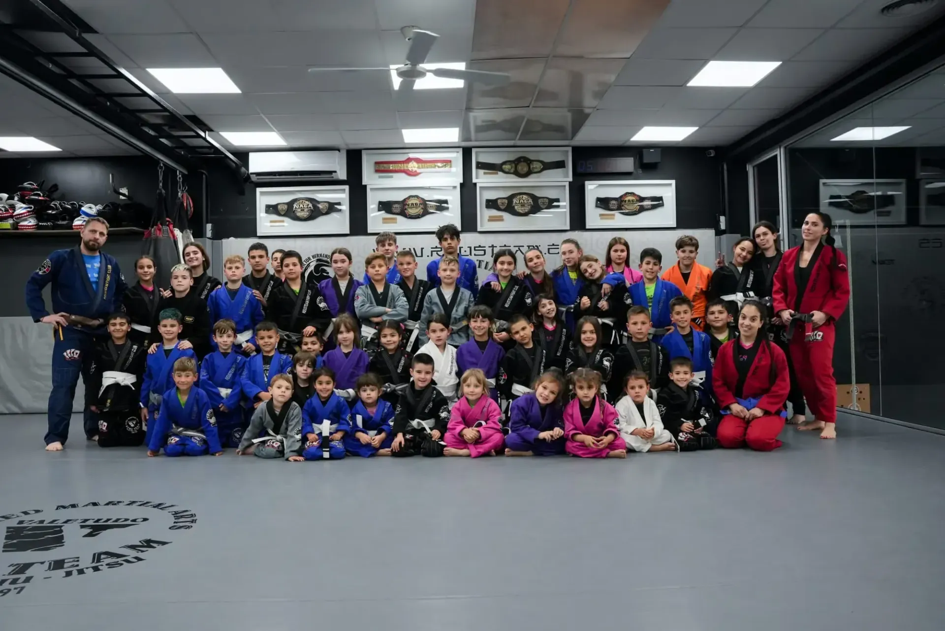 Dos luchadores de jiu-jitsu forcejeando sobre colchonetas azules y amarillas, uno con la de azul y el otro con la de blanca.