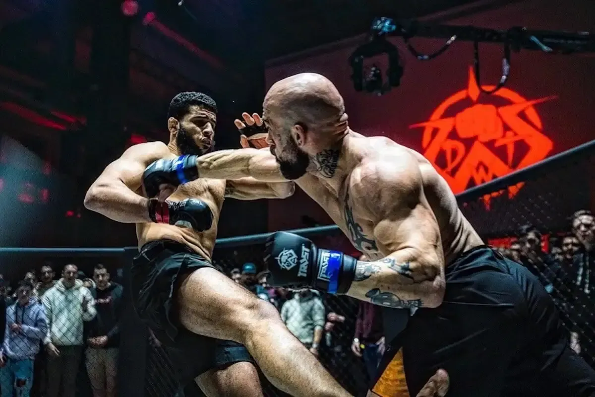 Dos luchadores intercambian golpes en un ring durante un combate de artes marciales mixtas.