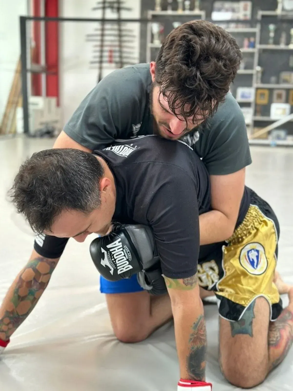 Dos hombres practican lucha cuerpo a cuerpo sobre una colchoneta