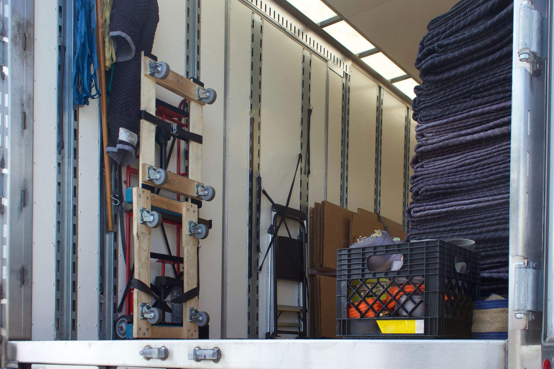 À l'intérieur d'un camion de déménagement, avec divers objets emballés : un diable, des caisses d'oranges, des cartons.