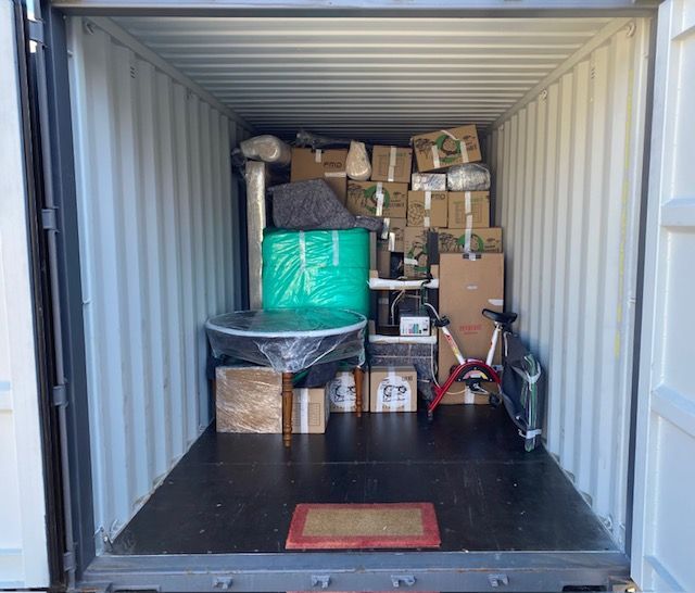 Un conteneur maritime rempli de cartons, de meubles et d'un vélo.