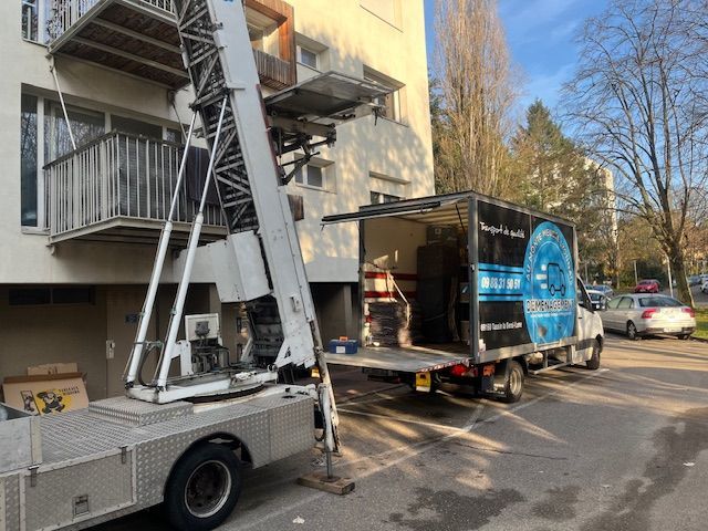 Camion de déménagement équipé d'un hayon élévateur, chargeant des meubles depuis le balcon d'un appartement.
