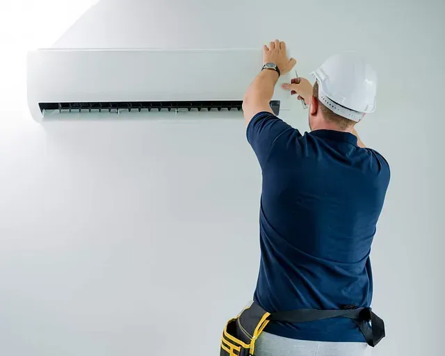 Un hombre está instalando un aire acondicionado en una pared.