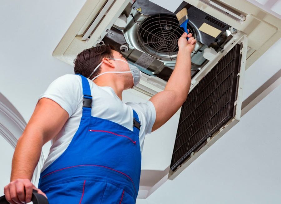 Un hombre que lleva una máscara está trabajando en un aire acondicionado.