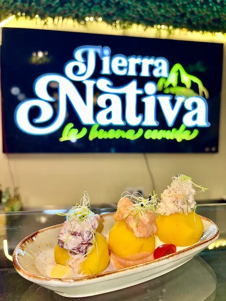 Plato de papas rellenas con el cartel de Tierra Nativa de fondo.