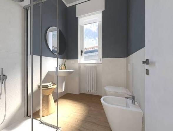 Bagno moderno con doccia in vetro, lavabo a colonna, specchio a parete, finestra, termosifone e vasca da bagno.