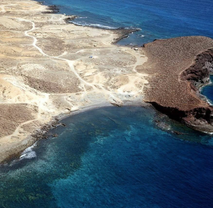 Vista aérea de una costa rocosa que se encuentra con el océano azul profundo.