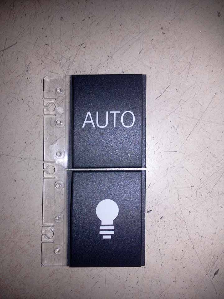 Interrupteur de voiture noir avec l'inscription « AUTO » et une icône d'ampoule.