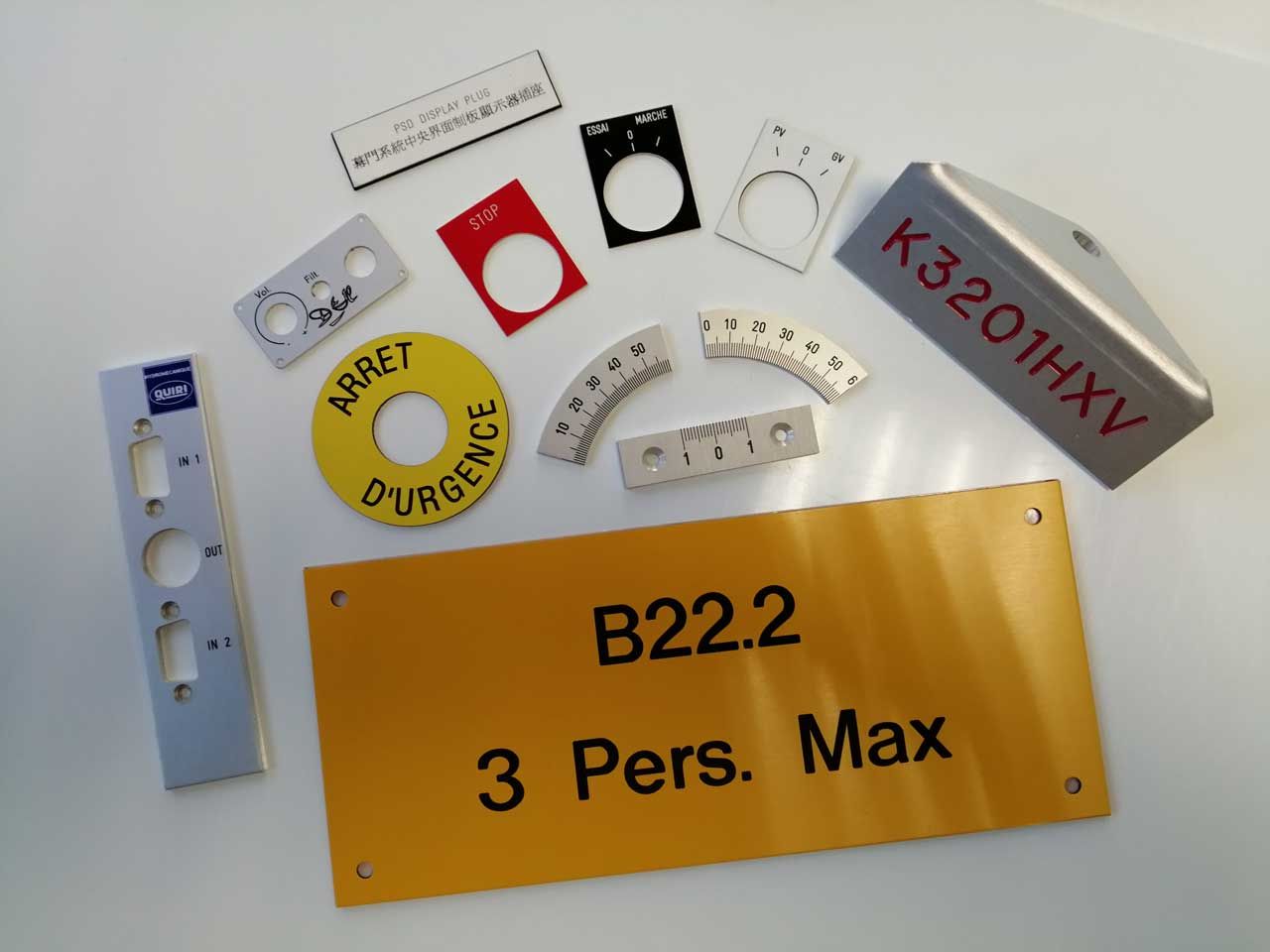 Diverses étiquettes et plaques métalliques pour panneaux de commande, de couleur argent, jaune, rouge et noire, avec texte et perforations.