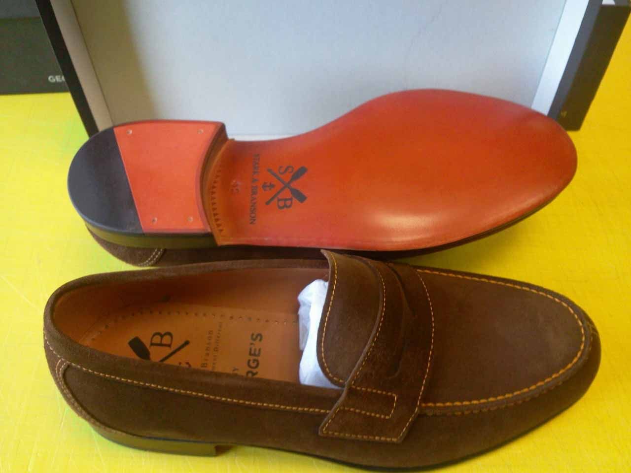 Mocassins en daim marron avec semelle et talon orange, dans une boîte.