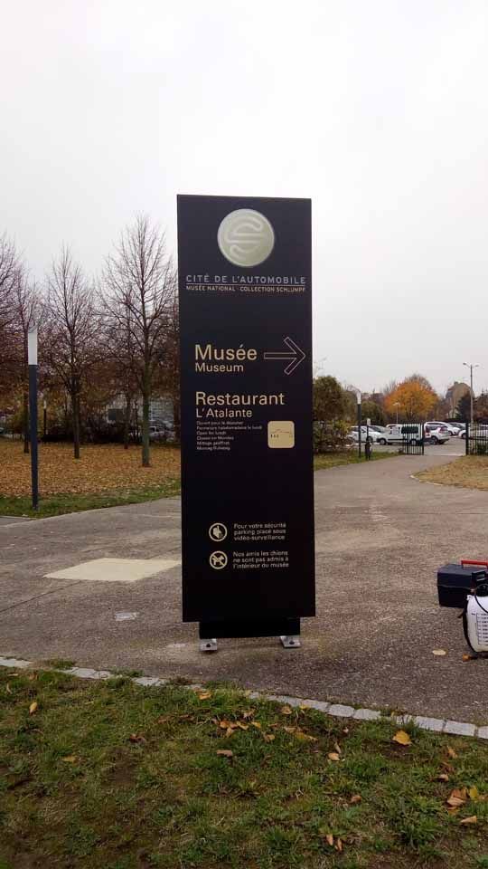Panneau directionnel noir avec flèche indiquant le musée et le restaurant.