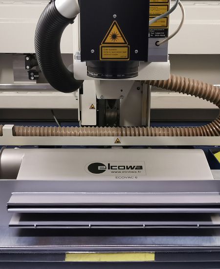 Machine de découpe laser avec tête laser et système de ventilation.