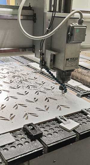 Machine CNC découpant un motif dans une feuille de métal.