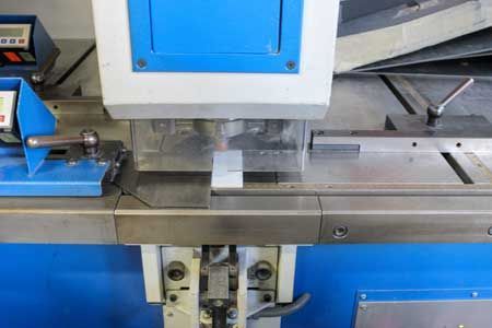 Machine de fabrication métallique avec une pièce en place. Bleue et argentée.