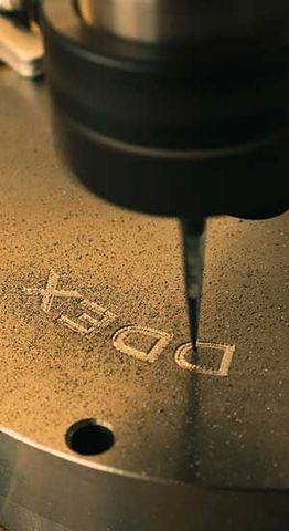 Gravure de la lettre « DDEX » sur une surface métallique par une machine CNC.