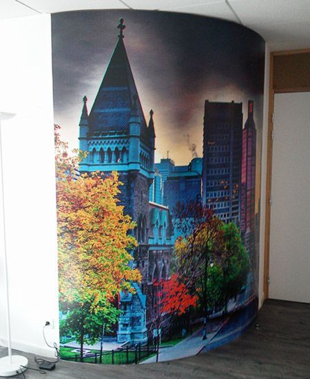 Fresque murale sur un mur incurvé représentant une cathédrale, des arbres d'automne et des gratte-ciel dans un décor coloré et spectaculaire.
