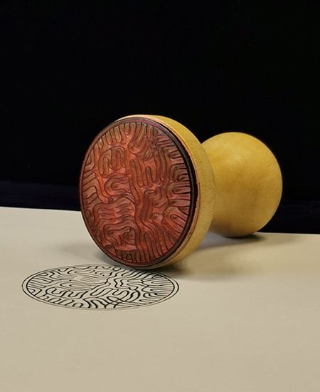 Tampon en bois à base circulaire à motifs, imprimant une empreinte détaillée sur le papier.